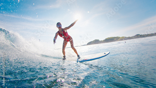 Canvas Print Woman surfer rides the ocean wave in the Maldives at sunset
