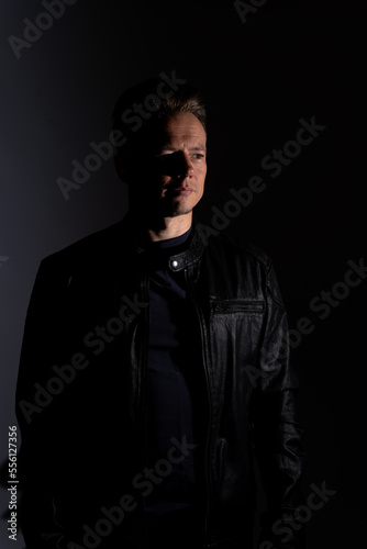 Portrait of handsome male. Sexy stylish man dressed in a leather jacket and sunglasses. Fashion hipster male isolated on grey background in studio © Collins Photography