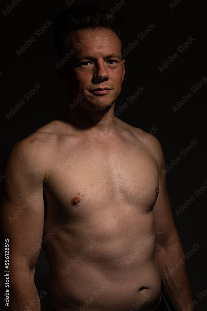 Sexy portrait of muscular handsome topless male isolated against a black background Sexy portrait of muscular handsome topless male isolated against a black background