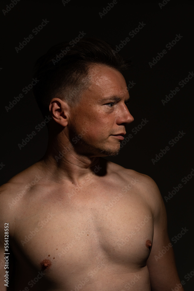Sexy portrait of muscular handsome topless male isolated against a black background Sexy portrait of muscular handsome topless male isolated against a black background