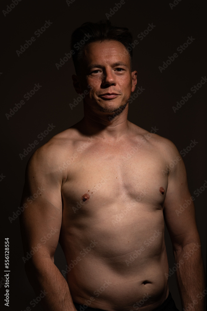 Sexy portrait of muscular handsome topless male isolated against a black background Sexy portrait of muscular handsome topless male isolated against a black background