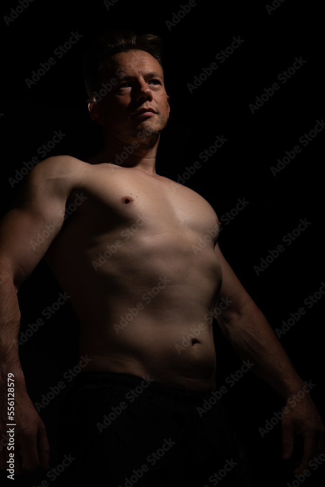 Sexy portrait of muscular handsome topless male isolated against a black background Sexy portrait of muscular handsome topless male isolated against a black background