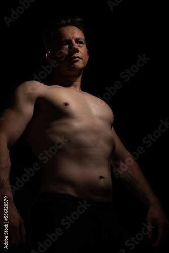 Sexy portrait of muscular handsome topless male isolated against a black background © Collins Photography