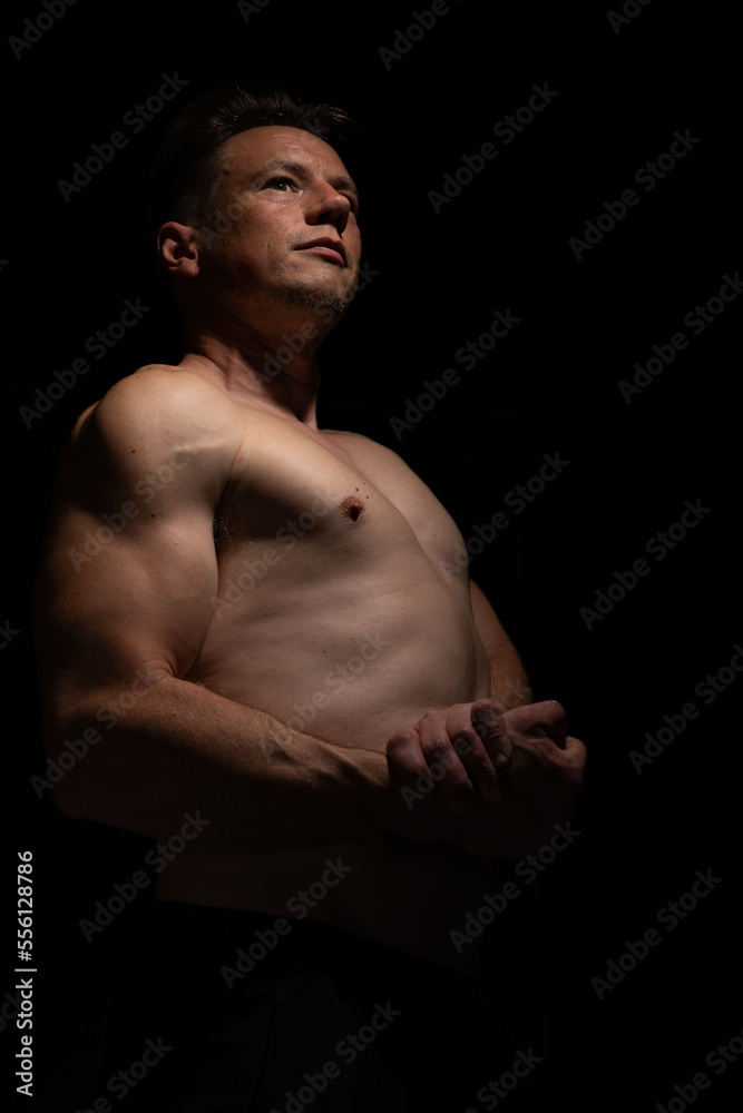 Sexy portrait of muscular handsome topless male isolated against a black background Sexy portrait of muscular handsome topless male isolated against a black background