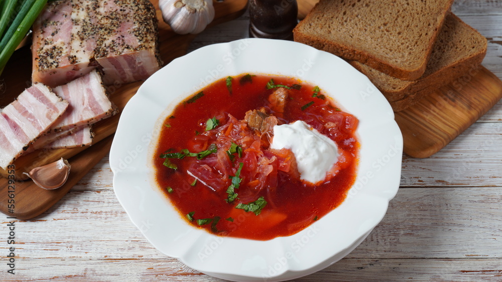 Traditional Ukrainian borscht . White plate of red beet root soup borsch with white cream, green onion, sliced salted pork lard (salo). Beet Root delicious soup. Traditional Ukraine food cuisine Traditional Ukrainian borscht . White plate of red beet root soup borsch with white cream, green onion, sliced salted pork lard (salo). Beet Root delicious soup. Traditional Ukraine food cuisine