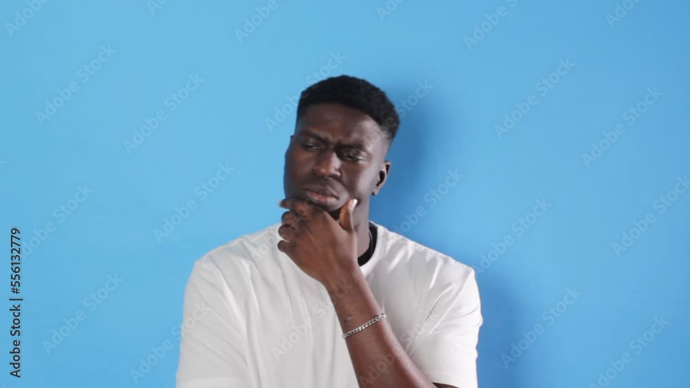 an African man looks thoughtfully into the camera on an isolated blue background. an African man looks thoughtfully into the camera on an isolated blue background.
