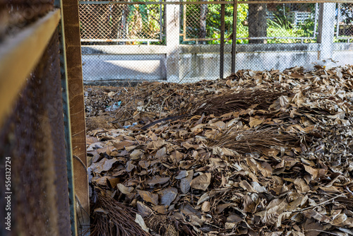 A large amount of dead leaves are piled together in the old steel grate structure room.