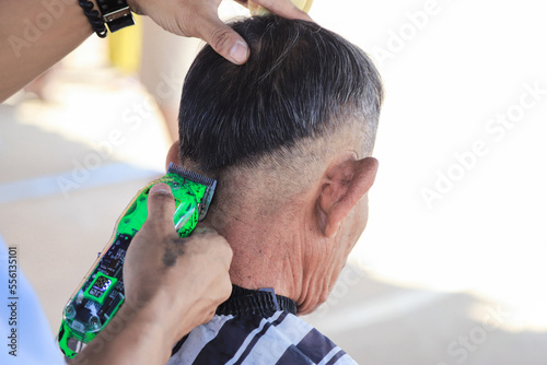 Barber using cutting hair clipper to cut at back view of head for making style. selective focus.