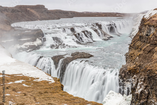 panoramica di Gullfoss, la cascata di acqua che scorre tra ghiaccio e neve in primavera durante il disgelo photo