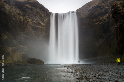 sk  gafoss  la cascata in lunga esposizione a formare una tenda d acqua con visibile il fiume e i sassi su cui c    la sagoma di un uomo solo