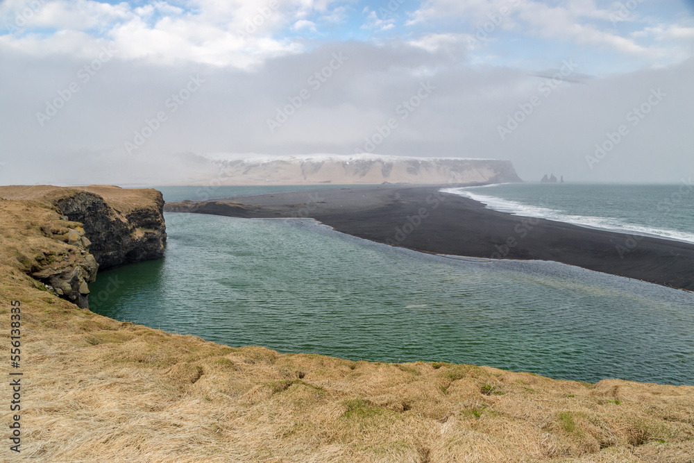 Fototapeta premium A rock outcrop that emerges from the black beach - Reynisfjara Beach