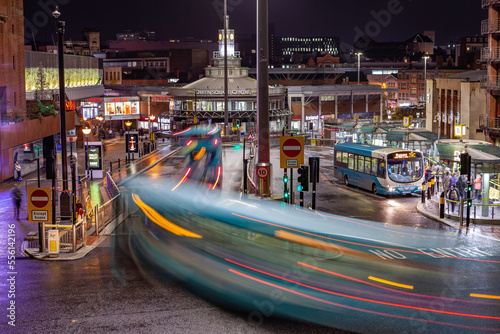 Busy bus station at night, long exposure light streaks from traffic photo