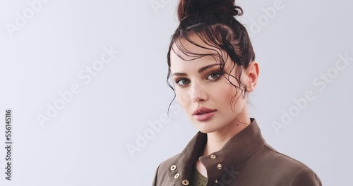 Beautiful young woman  with stylish hairstyle posing at studio. Close-up face of a girl with bright fashionable make-up. Fashion model with beautiful eyes  looks to the camera. Sexy girl. Slow motion.
