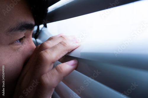 Obraz na plátne Man peeping outside through window or blind.