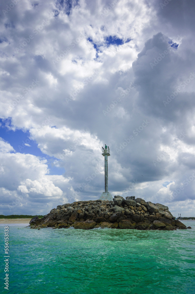 Ligth beacon on a rocks mound in beach and big clouds in the background Ligth beacon on a rocks mound in beach and big clouds in the background