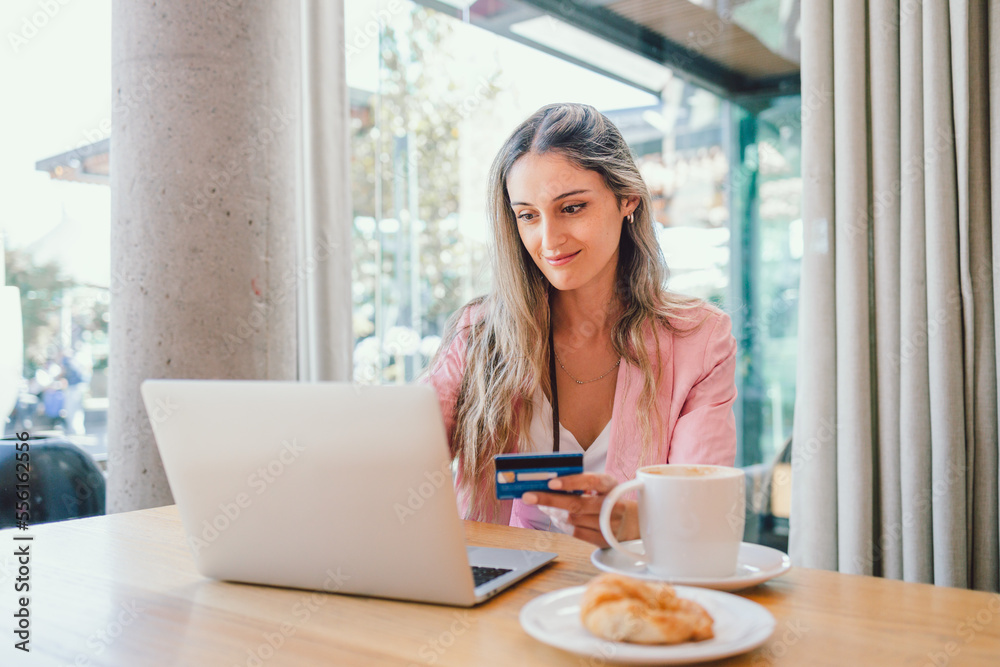 Young successful happy woman using a credit card to buy online outside a cafe. Online shopping 