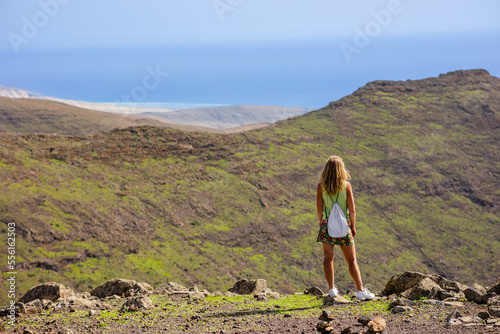 A traveler stands on the edge of a cliff and enjoys a stunning view of Fuerteventura against the backdrop of the mountain landscape of Jandia National Park, Canary Islands, Spain