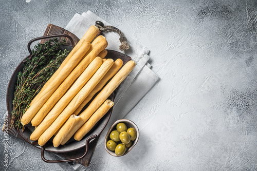 Italian grissini bread sticks in steel tray with herbs. White bakground. Top view. Copy space