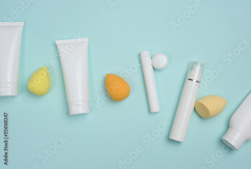 White plastic tubes for cream, gel and other cosmetics and sponges on a blue background