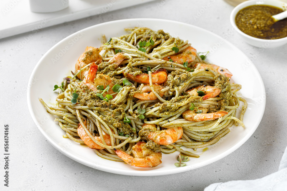 Spaghetti Pasta with shrimps, pesto sauce, prawns on white plate. Pasta with seafood, Mediterranean cuisine.