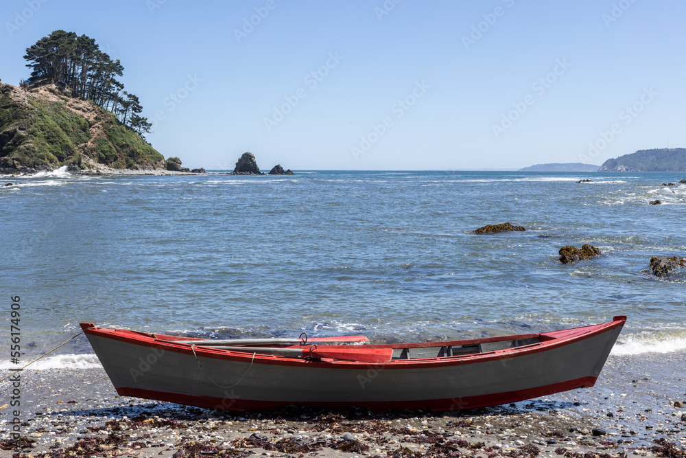 Red and white painted rowing boat at the beach at Isla Maiquillahue in the Pacific Ocean of Chile Red and white painted rowing boat at the beach at Isla Maiquillahue in the Pacific Ocean of Chile