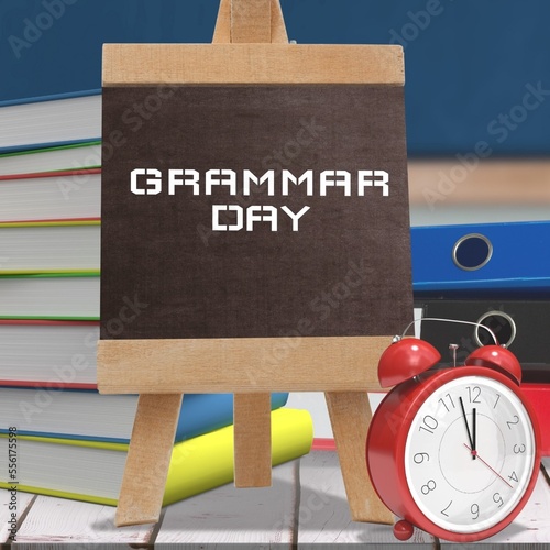 Files, stack of books and alarm clock on wooden table against grammar day text banner on easel
