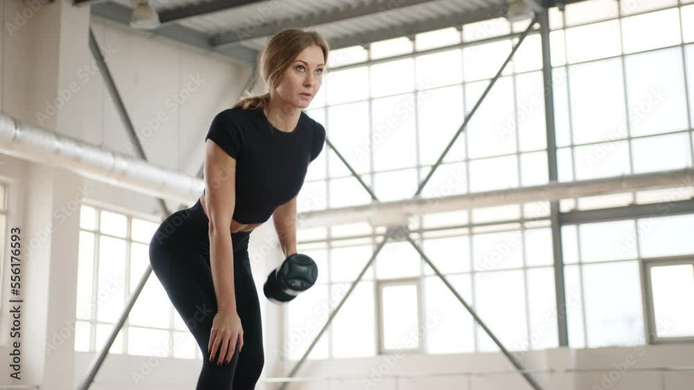 Female athlete working out with heavy kettlebell indoors. Young, blonde-haired woman lifting dumbbell in beautiful gym studio. High quality 4k footage Female athlete working out with heavy kettlebell indoors. Young, blonde-haired woman lifting dumbbell in beautiful gym studio. High quality 4k footage