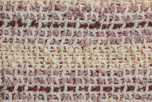 Background texture of a warm beige woolen scarf with brown threads.