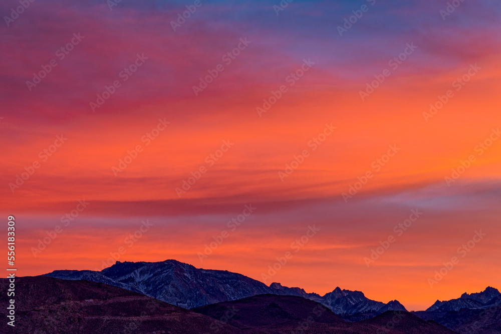 The setting sun illuminates the clouds over snow-capped mountains near Bishop, California, USA