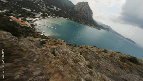 Cinematic shot from fpv drone. Sea and cliffy coast above. Rocky coastline aerial landscape. Descent along the cliffs to the sea. Black Sea in Crimea, Sudak. photo