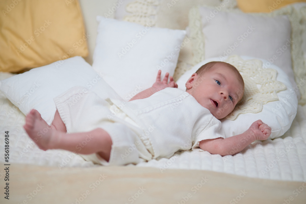 Newborn baby for the first time at home, lying in a blanket on the bed, smiling, yawning, pulling pens, falling asleep, baby's morning, baby products concept Newborn baby for the first time at home, lying in a blanket on the bed, smiling, yawning, pulling pens, falling asleep, baby's morning, baby products concept