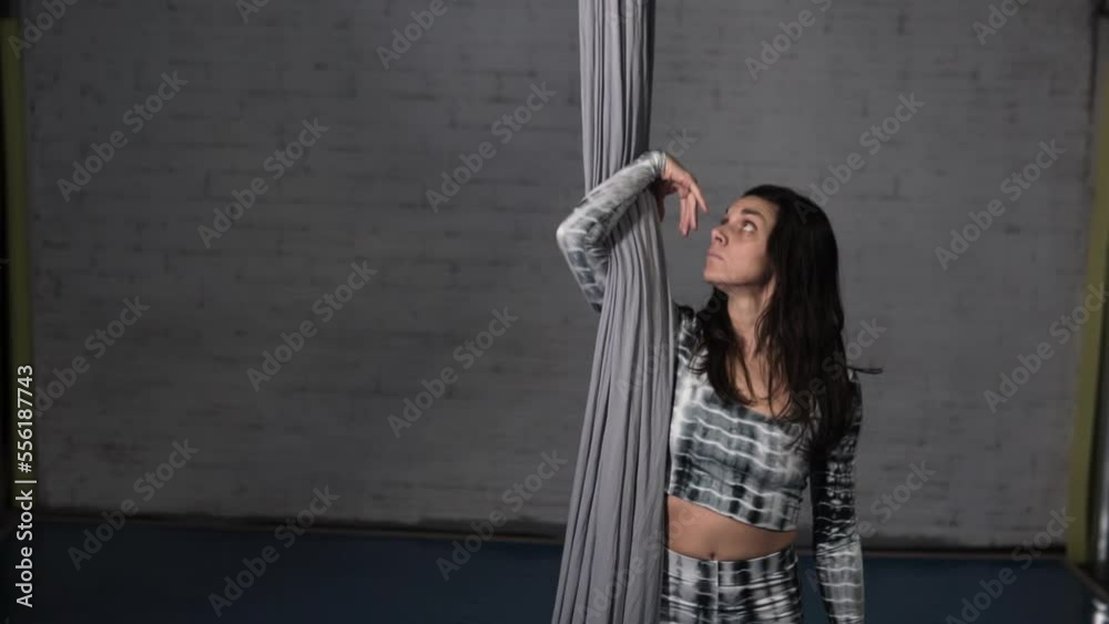 Young woman performs with a circus style against gray room. Aerial Silks dance. Young woman performs with a circus style against gray room. Aerial Silks dance.
