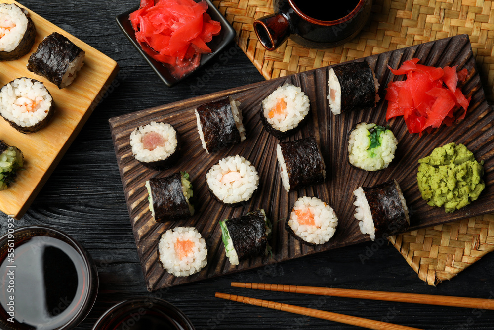 Tasty sushi rolls served on black wooden table, flat lay Tasty sushi rolls served on black wooden table, flat lay