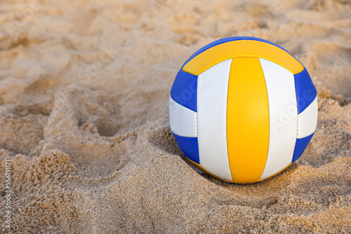 Colorful volleyball ball on sandy beach. Space for text