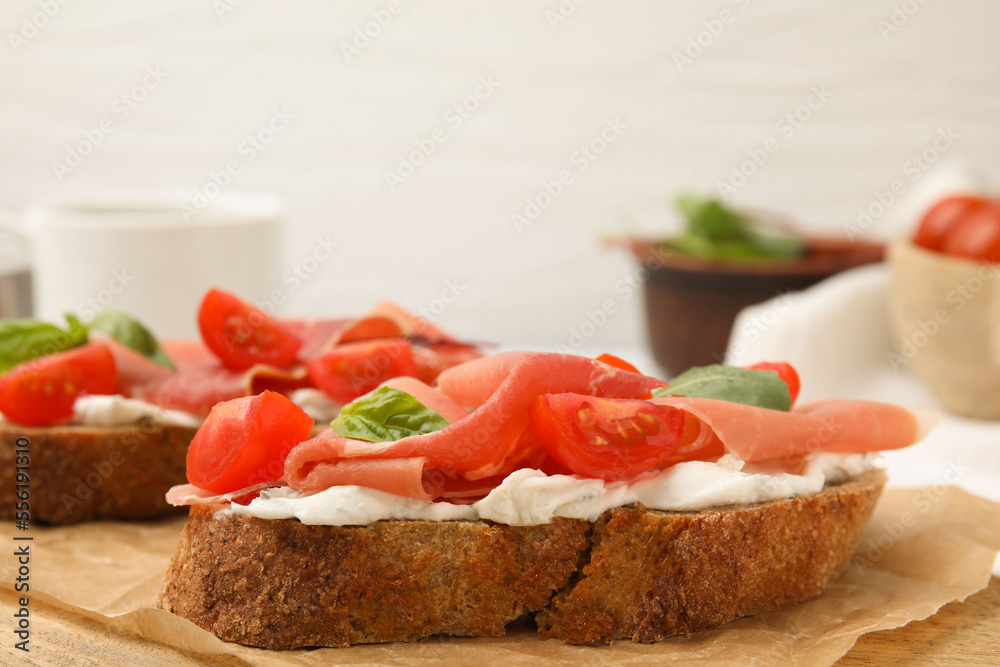Tasty bruschettas with prosciutto, tomatoes and cheese on wooden board, closeup Tasty bruschettas with prosciutto, tomatoes and cheese on wooden board, closeup