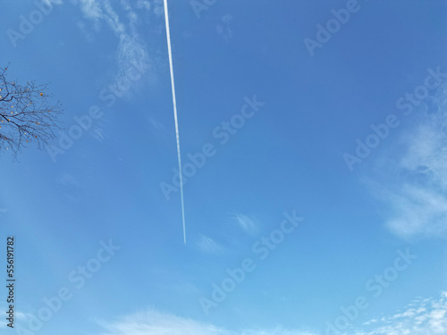 blue sky with clouds and airplane flying smoke trail