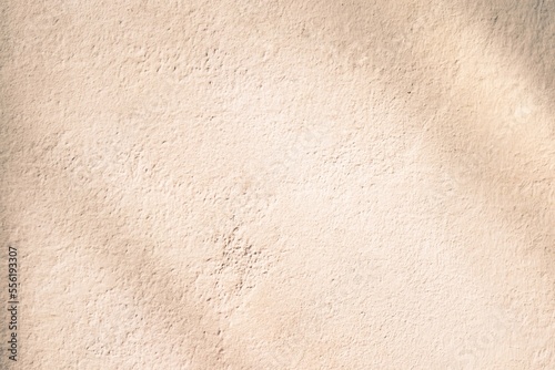 Brown cement wall background texture with natural slanted sun shadows.