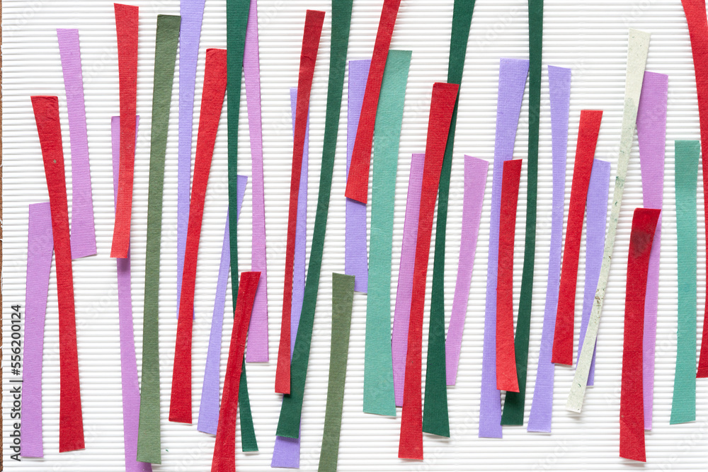 abstract paper background with short paper stripes mostly in red, mauve, and green on white corrugated paper abstract paper background with short paper stripes mostly in red, mauve, and green on white corrugated paper