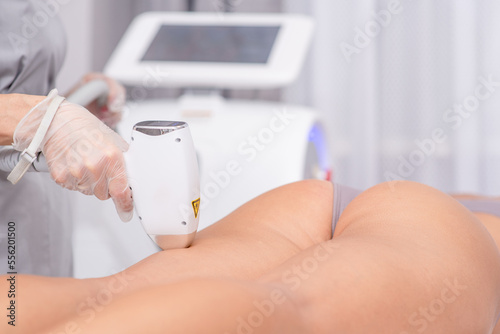 Slika na platnu Professional beautician removes hair on beautiful female buttocks using a laser