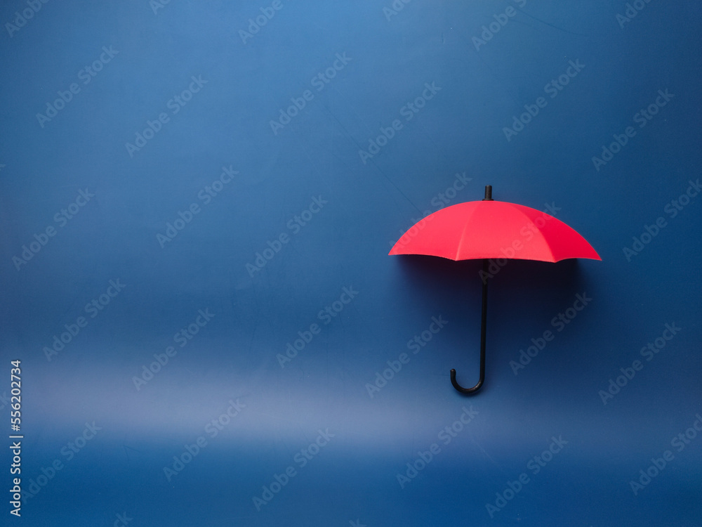  A red umbrella on a blue background with copy space., planning, saving families, preventing risks and crises, health care and insurance concepts.