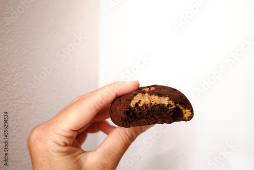 Woman's hand showing a fluffy thick chocolate brownie cookie cut in half with peanut 