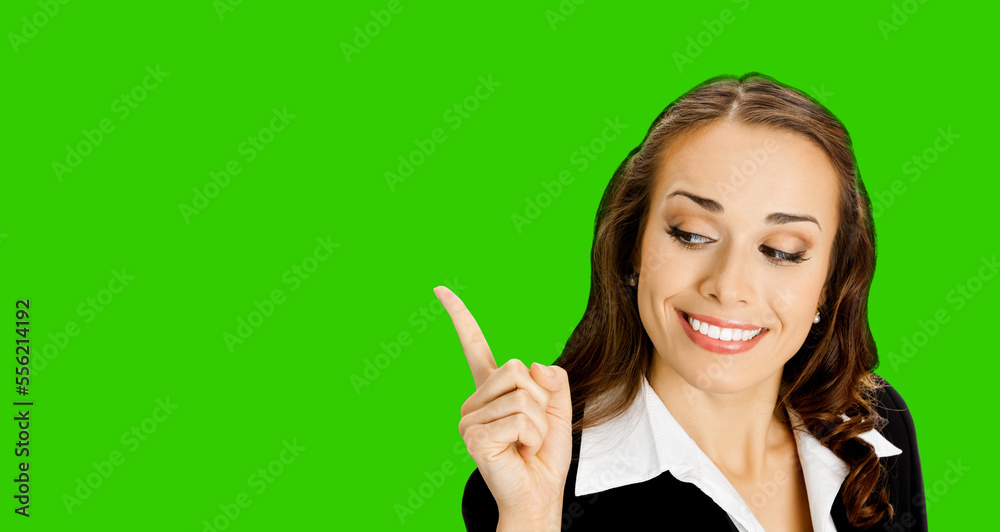 Happy smiling executive woman in black confident suit, pointing showing indicating copy space. Business concept. Brunette businesswoman. Green chroma key background.