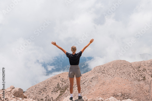 The girl stands on the edge of a high mountain in the clouds. The girl looks at the beautiful mountain landscape Antalya Turkey