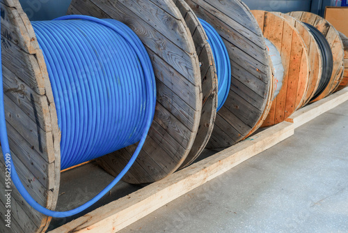 New blue power cable is wound on wooden coil. Background. Cable for laying underground..