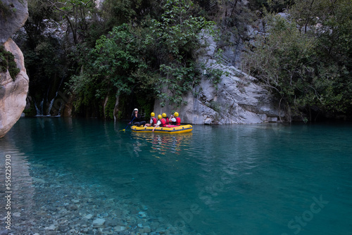Group of tourists on a rafting boat in Göynük Canyon.Tourists and guide on an inflatable boat rafting down the blue water.