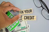 paper money, calculator and glasses with the words fix your credit. Credit repair is the act of restoring or correcting a poor credit score.
