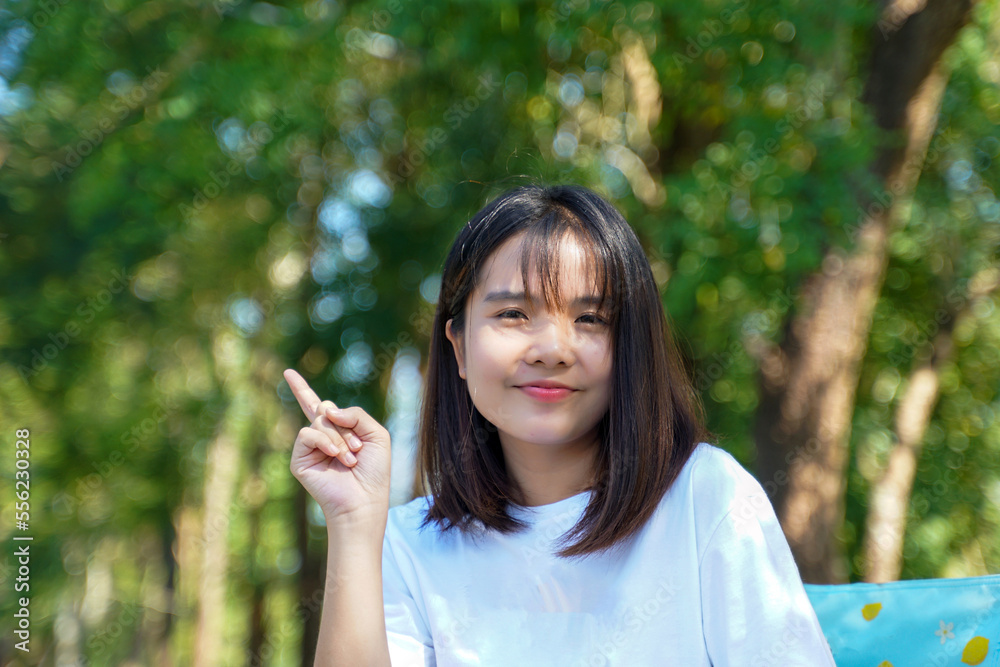 Asian woman Catch up on ideas while reading a book on a lawn chair in the park. concept doing outdoor activities such as reading, working, listening to music, having a picnic, etc. Asian woman Catch up on ideas while reading a book on a lawn chair in the park. concept doing outdoor activities such as reading, working, listening to music, having a picnic, etc.