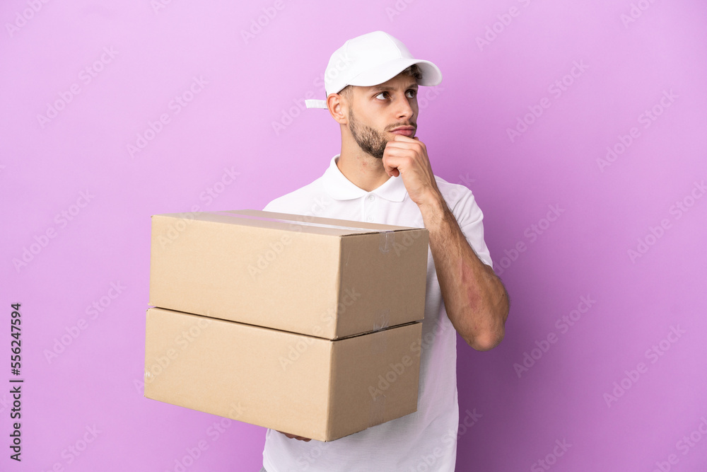 Delivery caucasian man isolated on purple background and looking up Delivery caucasian man isolated on purple background and looking up