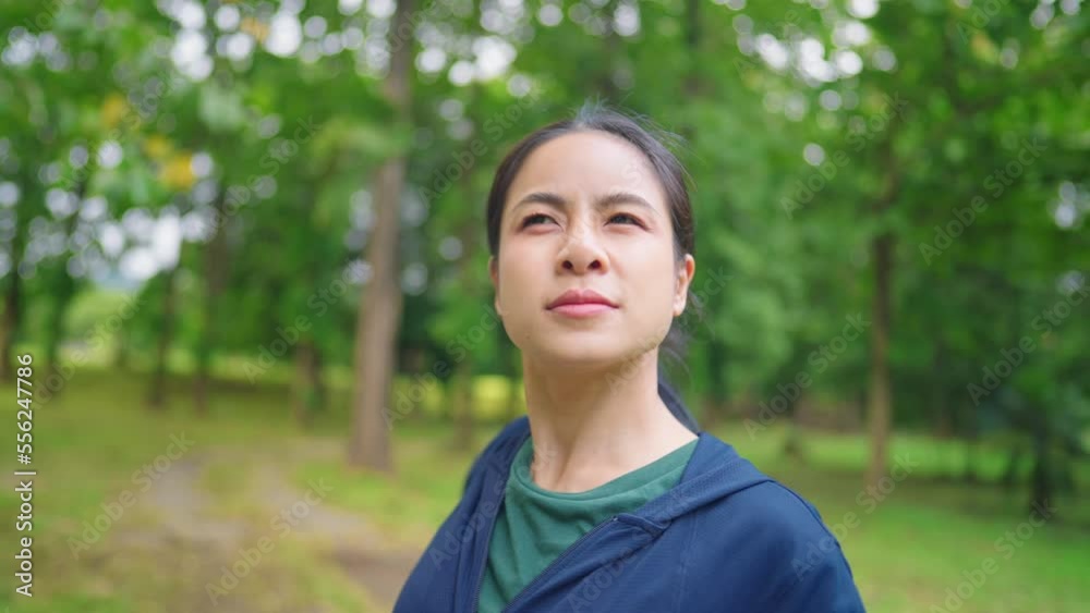 Asian woman doing exercise alone inside the forest park, body warm up before exercise, walking under trees, muscles flexibility rotate arms and shoulders, office syndrome remedy, wellness vitality 