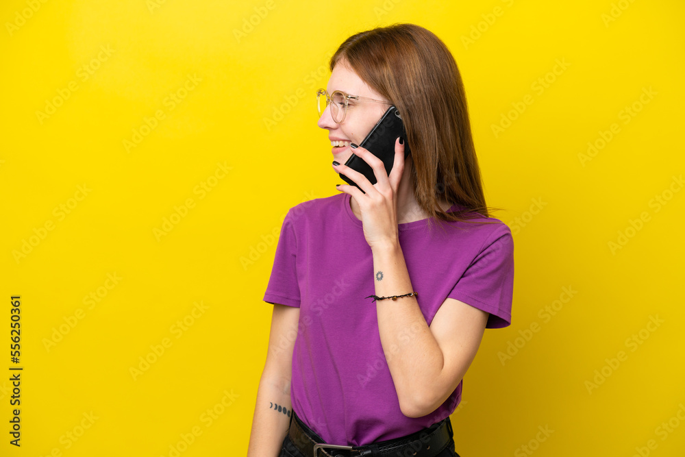 Young English woman isolated on yellow background keeping a conversation with the mobile phone with someone Young English woman isolated on yellow background keeping a conversation with the mobile phone with someone